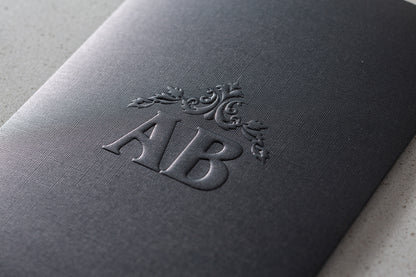 İklim Davetiye 10693 - Rölyef baskı monogram ve rozet motif detayı, antrasit gri kabartmalı davetiye kapağı