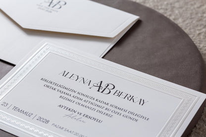 İklim Davetiye 10708 - Kabartmalı bordür ve serif monogram detay görünümü, beyaz kart yakın çekim